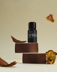 Vitruvi Spruce essential oil bottle on a beige background with decorative elements.