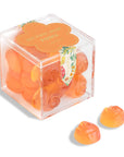 Clear cube box with orange rose-shaped candies on a white background