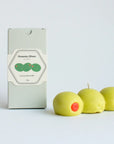 Candle shaped like pimento olives with a box labeled 'Pimento Olives' on a light gray background