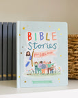 Children's book titled 'Bible Stories for Little Ones' on a shelf with other books and a basket.