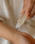 Person applying Wiley Body product to their arm with a roller bottle.