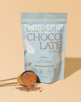 Packaging of 'Drinking Chocolate' with a scoop of powder on a beige background
