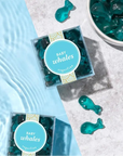 Blue whale-shaped gummy candies in clear packaging on a light blue and gray surface.