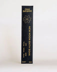 A tall, narrow black box for Ollie Blossom New Moon Bath Soak, featuring gold text and a gold outline flower logo, photographed against a clean white background.