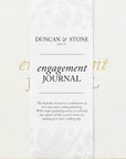 white textured journal with gold lettering that says "engagement journal"