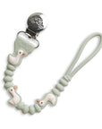 A silicone baby pacifier clip with a mint green beaded strap, featuring three small white duck figures with orange beaks and a silver metal clip.