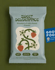A package of Sweet Deliverance Strawberry & Salty Peanut Granola sits on a solid olive green background. The packaging is a dusty light blue-gray color with dark green text and an illustration of strawberries and vines.