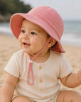 baby wearing a pink bucket hat on the beach