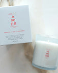 Candle and packaging with 'ARIES' branding on a neutral background