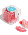 Pink candy shaped like lips in a clear box with a blue label on a white background