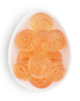 Orange rose-shaped candies on a white plate with a white background