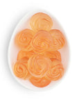 Orange rose-shaped candies on a white plate with a white background