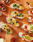 Assorted crostini with various toppings on a wooden surface