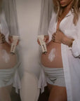 Pregnant woman holding and applying Revitalizing Stretch Mark Cream