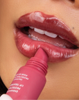 woman applying berry colored lip gloss tube on her lips