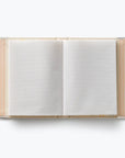 An open notebook with blank white pages, bound with a clear plastic cover and decorated with pastel stripes in pink, orange, and yellow on the left and right edges, shot from a top-down view on a white background.