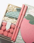 Stationery set with pink strawberry-shaped sticky notes, pens, and decorative items in a box.
