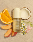 Kit-sch Coastal Sorbet perfume bottle surrounded by fruit slices and flowers on a beige background