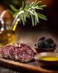 Sliced salami on a wooden board with blackberries and olive oil.