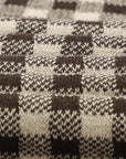 Close-up of a knitted fabric with a houndstooth pattern in brown and beige.
