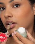 Woman applying lip balm with a visible 'Allure Best of Beauty Award Winner' badge.