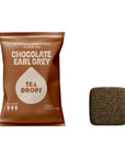 A package of Tea Drops Chocolate Earl Grey black tea drops next to a single square dark brown tea drop on a white background.