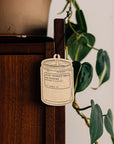 Air freshener tag on a wooden surface with a plant in the background
