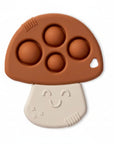A mushroom-shaped baby teether or sensory toy with a brown cap featuring four raised bubble circles and a cream-colored stem with a smiling face, shown on a white background.