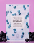 Vitamasques Niacinamide Blueberry sheet mask packaging on a pink background with blueberries.