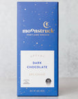 A blue box of Moonstruck Dark Chocolate, labeled as 'Dreamy Dark Chocolate 68% Cacao.' The box design includes white and gold star-like specks, with the text 'Portland Oregon' beneath the Moonstruck logo. The label notes that the chocolate is made with all-natural ingredients and carries the Cocoa Horizons Foundation logo
