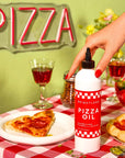 Person holding a bottle of pizza oil over a pizza on a checkered tablecloth with a 'PIZZA' sign in the background.