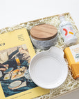 Gift box with a magazine, ceramic items, and a bottle of wine on a white background