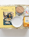 Gift box with 'al fresco' magazine, cutting board, and other items on a white background