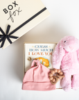 Baby gift set with pink hat, elephant plush toy, and book titled 'Guess How Much I Love You' on a white background.