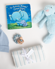 Collection of baby items including a book, hat, rattle, and blanket on a white background