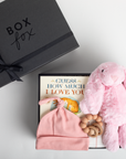 Baby gift set with pink hat, plush toy, and book next to a black 'Box Fox' gift box.
