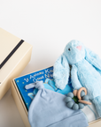 Baby gift set with blue plush bunny, book, and teether on a white surface