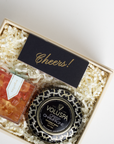 Decorative candle with 'Cheers!' card and Voluspa branding in a gift box.