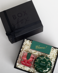 Gift box with 'Box Fox' branding, containing a card and two small containers on a white background.