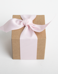 Gift box wrapped in brown paper with a pink ribbon on a white background