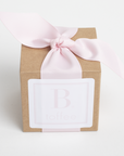 Gift box with a pink ribbon and a white label on a light gray background