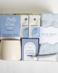 Gift set with mug, tea packages, shower steamers, and socks on a white background