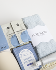 Assorted self-care items including tea packages, socks, and shower steamers in a box on a white background.