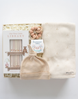 Baby hat, blanket, and book set on a white background