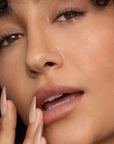 Close-up of a woman's face with a focus on her lips and nails.