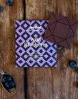Goodio Wild Blueberry chocolate bar on a wooden surface with blueberries and a spoon.