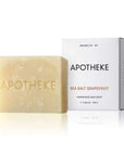A pale yellow bar of Apotheke Sea Salt Grapefruit handmade bar soap stands in front of its white packaging box on a clean white background.