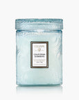 Light blue candle in a glass jar with Voluspa branding on a white background