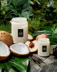 white glass jar candles next to coconuts and peaches
