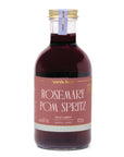 Clear bottle with red liquid and a gold cap with a label that says "rosemary pom spritz" in white writing